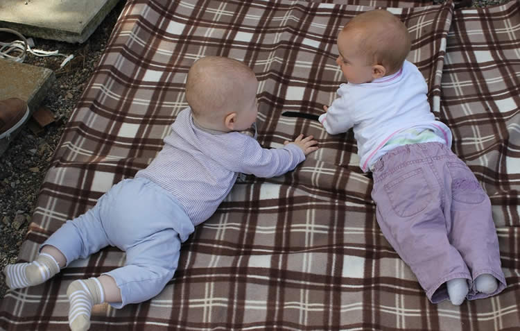 Image shows babies on a blanket.