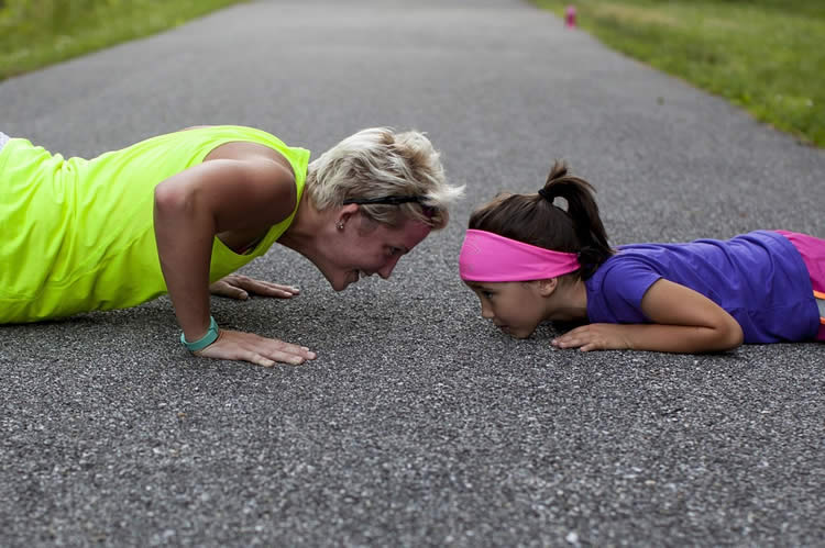 Image shows a woman and child doing push ups.
