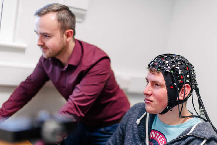 the researcher and a participant in an EEG helm