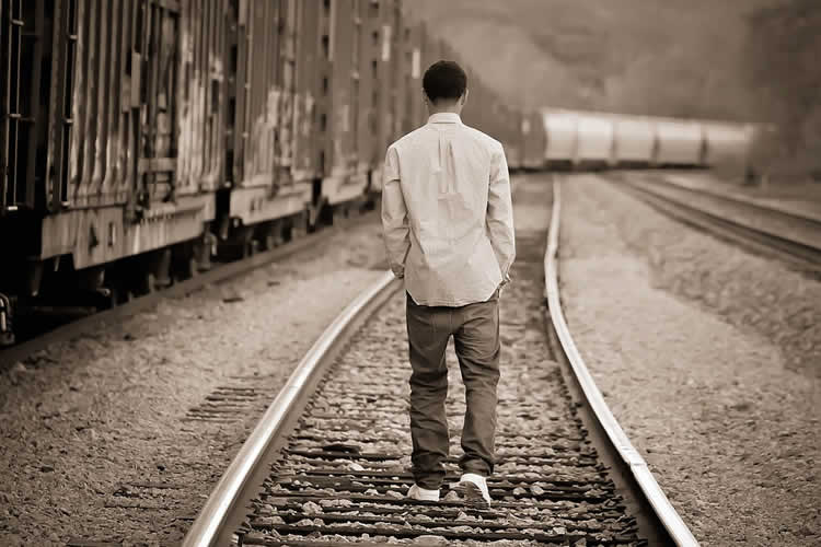 boy walking on train tracks