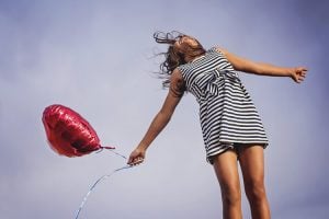 A person in a dress is shown holding a balloon.