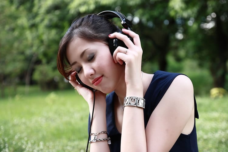 This shows a woman listening on headphones