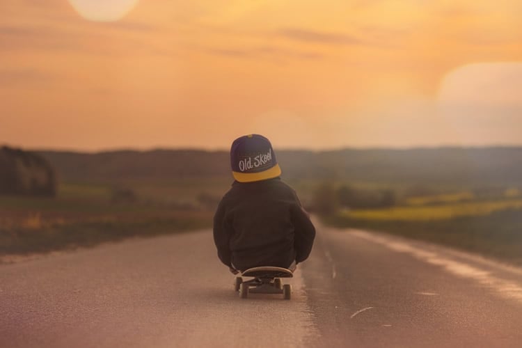 This shows a young boy sitting on a skate board