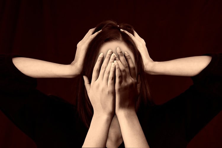 this is a woman holding her head while other hands are covering her face