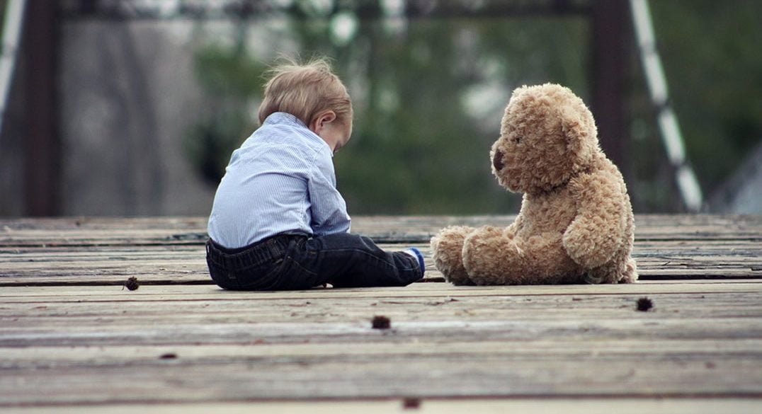 This shows a young child and a teddy