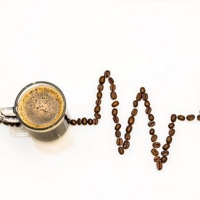 This shows a cup of coffee and coffee beans made to look like a heart rhythm line