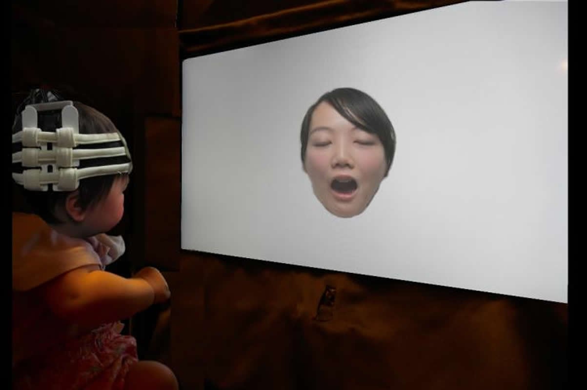 This shows a baby looking at a picture of a woman yawning