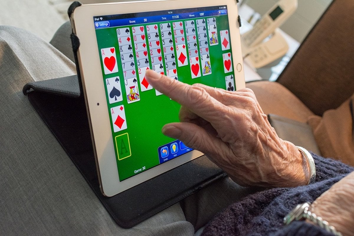 This shows an old man playing cards on a computer