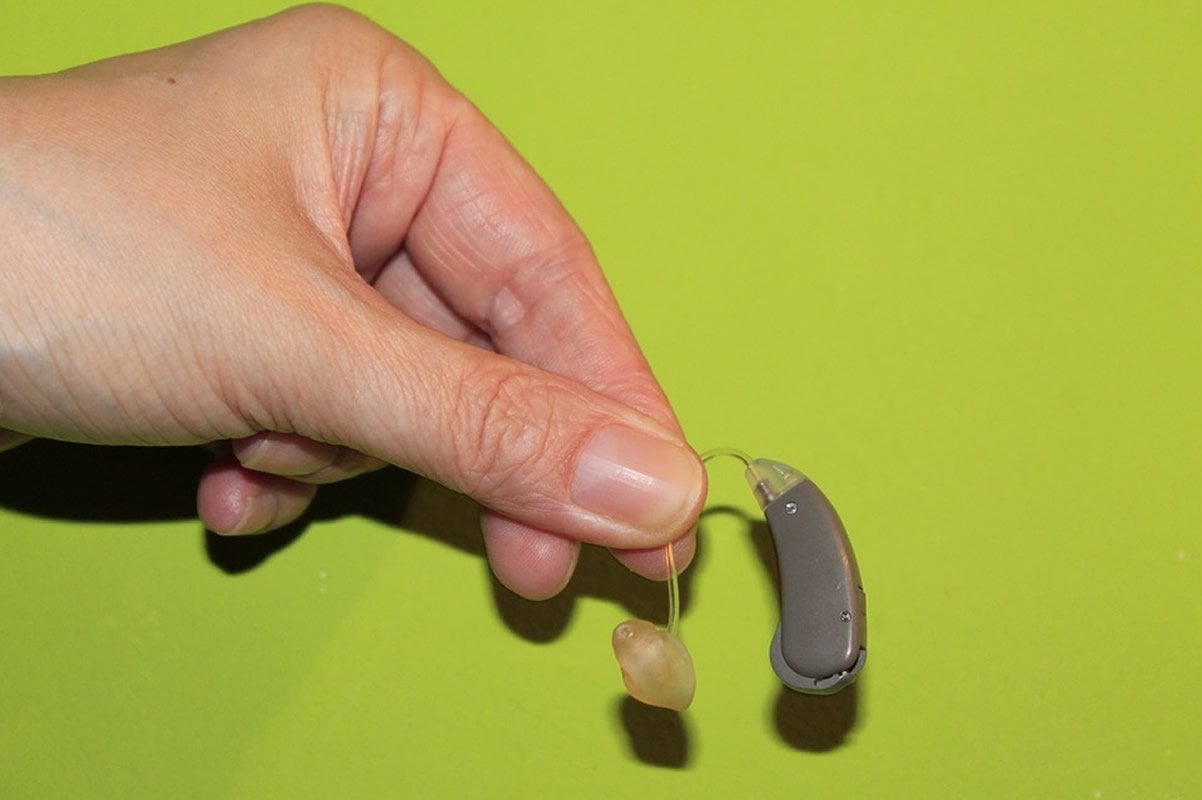 This shows a person holding a hearing aid in their fingers