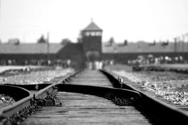 This shows the train track with the entrance to Auschwitz in the distance