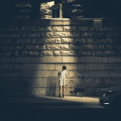 Image shows a child standing under a street lamp alone