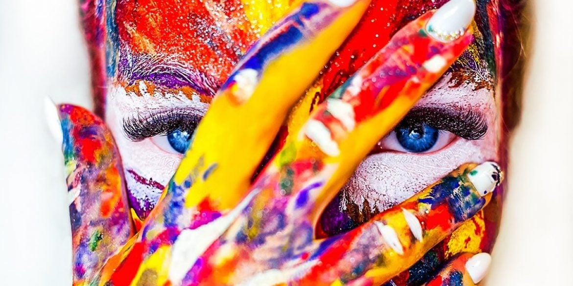 This shows a woman with her face painted multiple colors