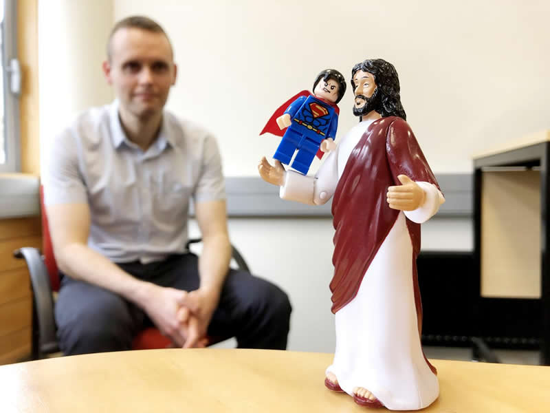 This shows a statue of jesus holding up a lego superman