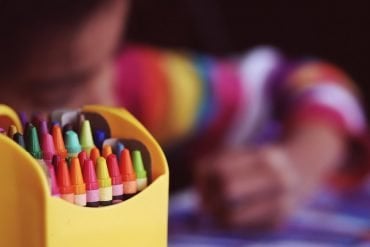 This shows a child coloring with crayons