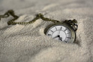 This shows a pocket watch in the sand