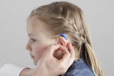 This shows a little girl with a hearing aid