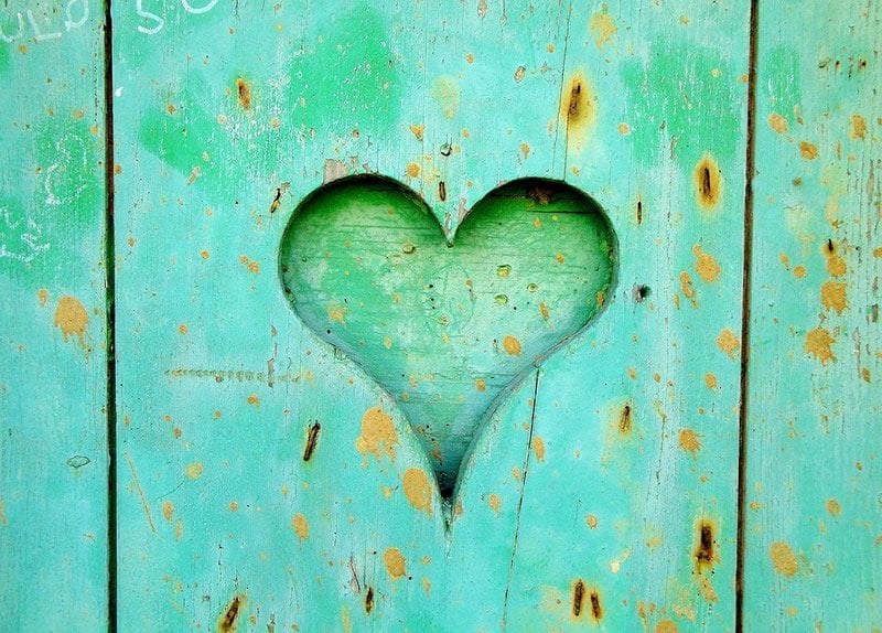 This shows a heart carved into a green wooden door