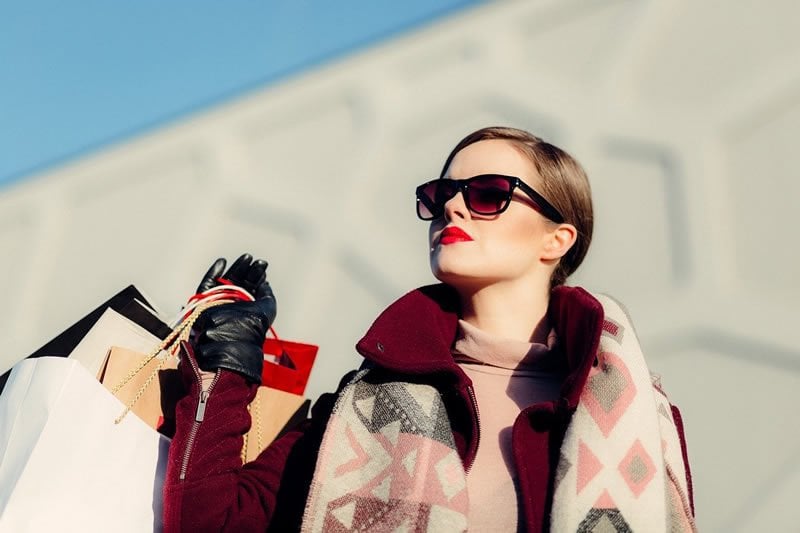 This shows a woman carrying shopping bags and wearing designer clothes