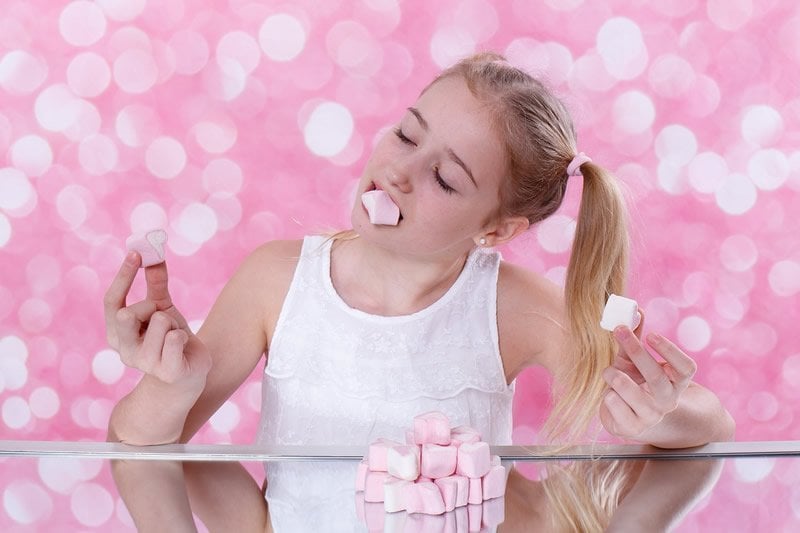 This shows a girl eating marshmallows