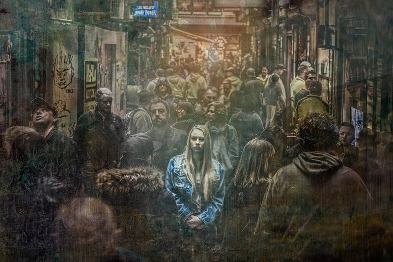 This shows a sad looking woman on a crowded city street
