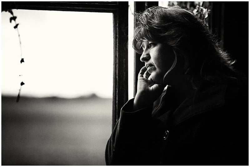 This shows a woman standing by a window