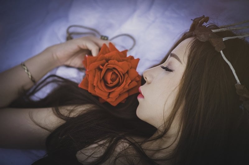 This shows a sleeping woman wiht a rose next to her nose