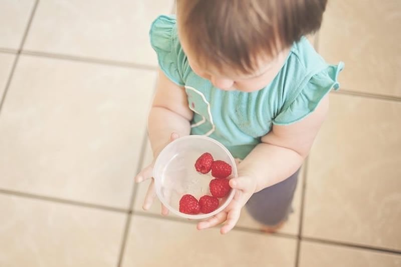 This shows a young child with a bowl of fruit