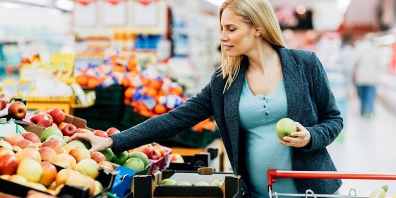 This shows a pregnant woman buying apples