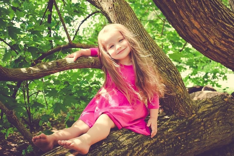 This shows a happy girl in a tree