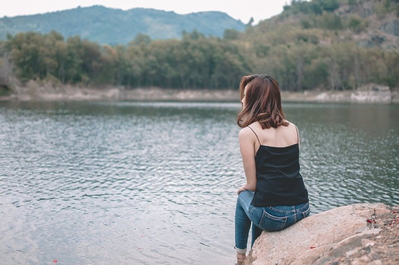 This shows a woman sitting by a lake