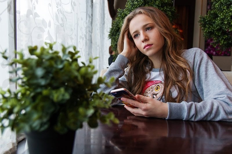 This shows a teen sitting down and using her phone