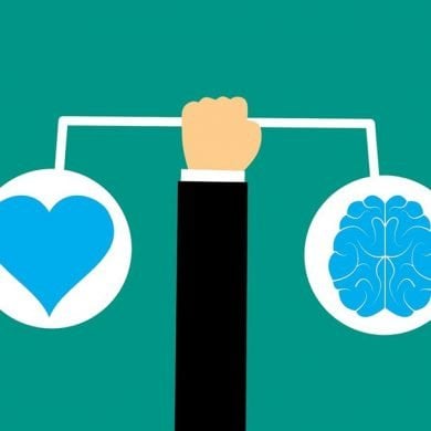 This shows a person holding a drawing of a heart and brain on a scale