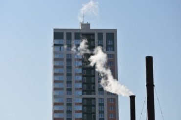 This shows an apartment building next to a smoke stack
