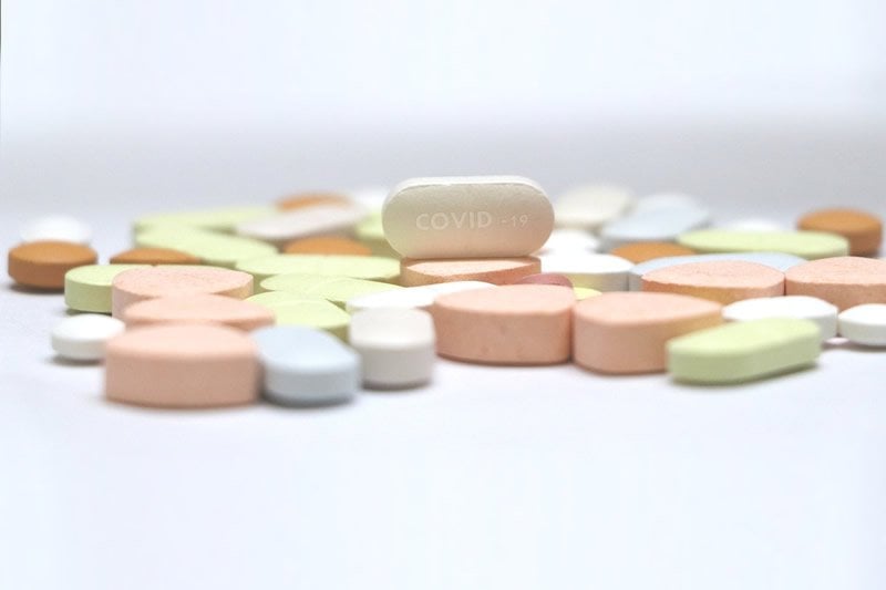 This shows a pill with COVID-19 written on it
