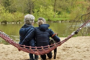 This shows an older person and a young person on a hammock