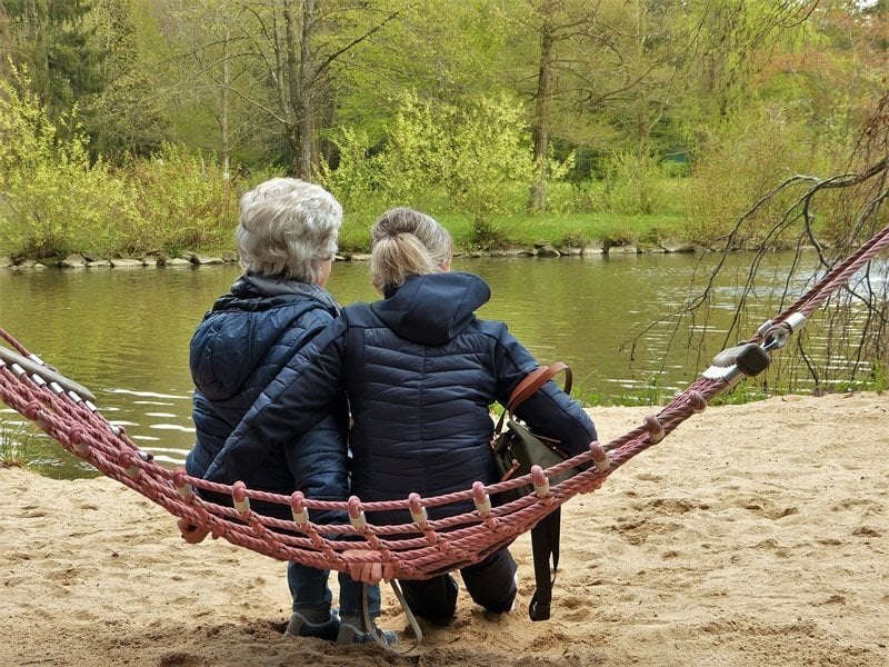 This shows an older person and a young person on a hammock