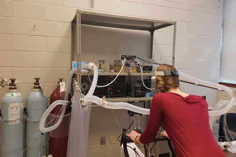 This shows a woman hooked up to breathing monitors while on an exercise bike