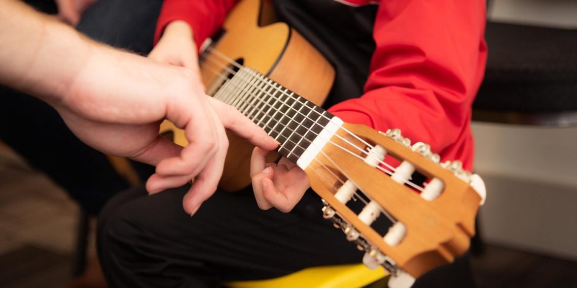 This shows a child learning guitar