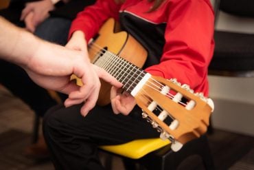 This shows a child learning guitar