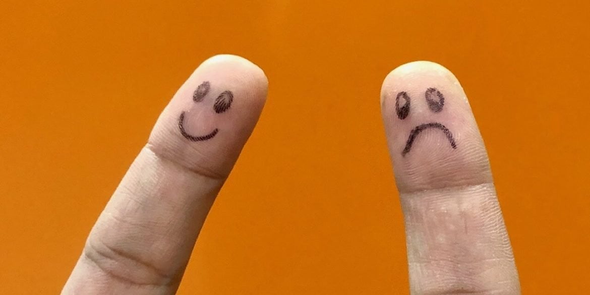 This shows two fingers, one has a smiley face drawn on it, the other has a frowning face