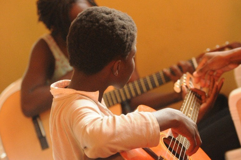 This shows two children playing guitars