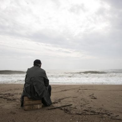 This shows a man sitting alone on a beach