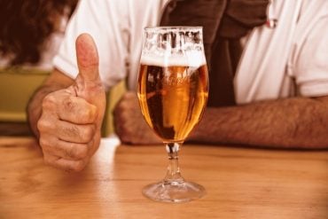 This shows a glass of beer and a man's thumb
