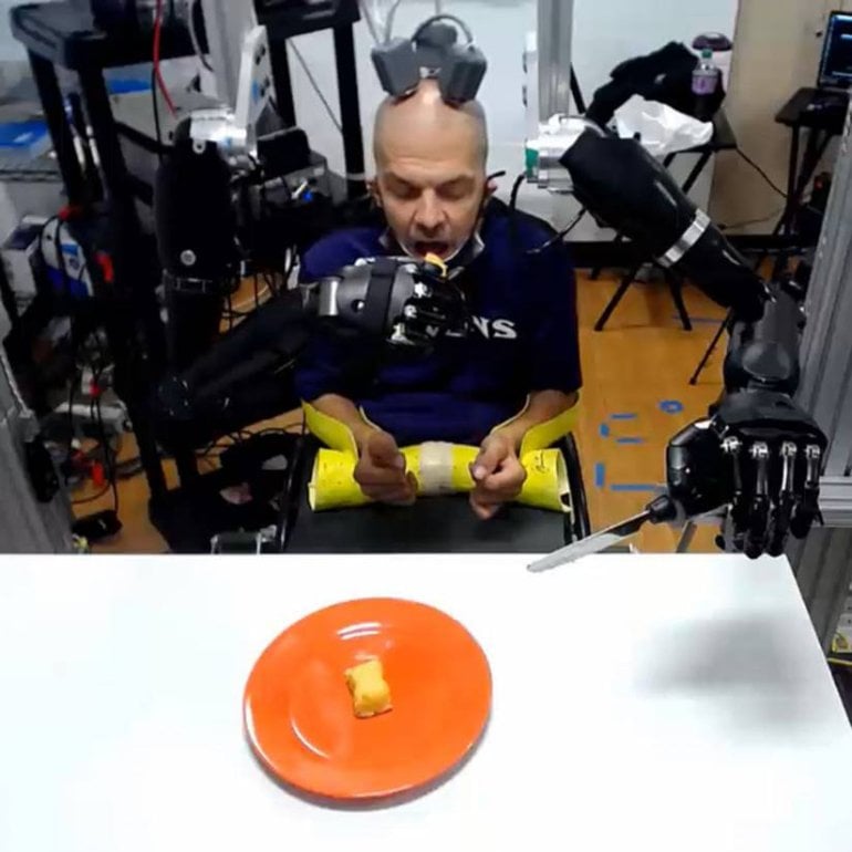 This shows the patient using the robotic arms to feed himself
