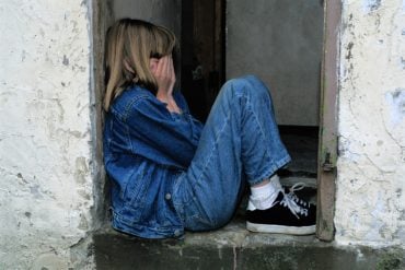 This shows a young girl crying and alone in a doorway