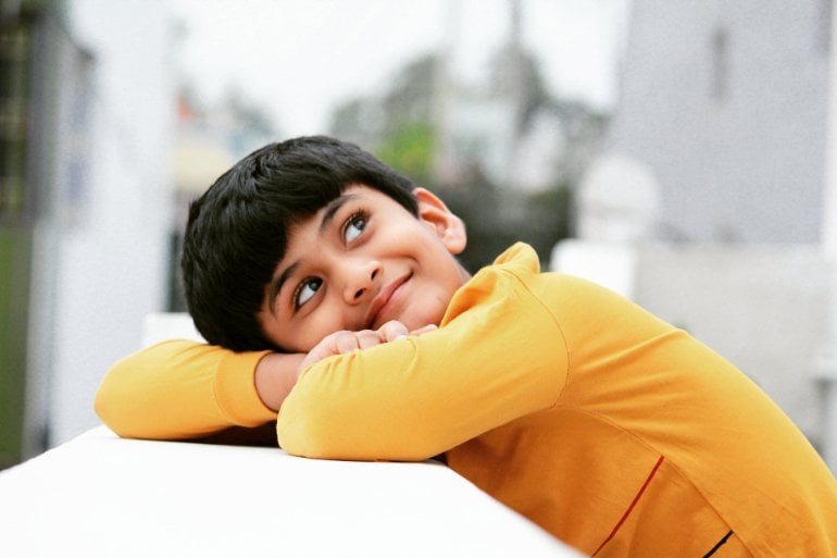 This shows a happy little boy, looking as though he is daydreaming