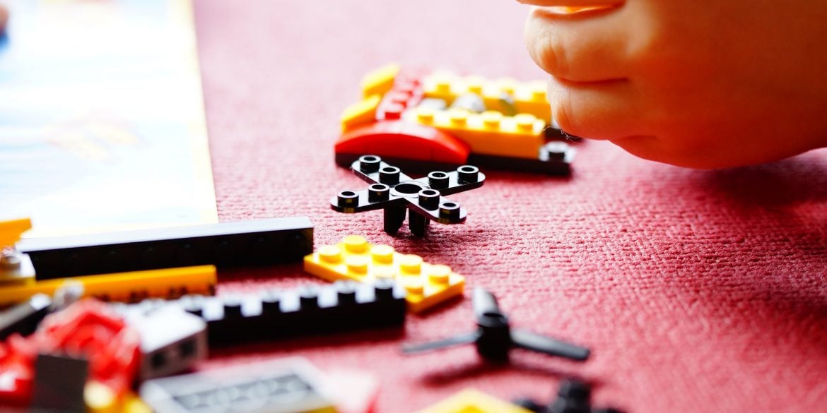 The image shows a child playing with lego blocks