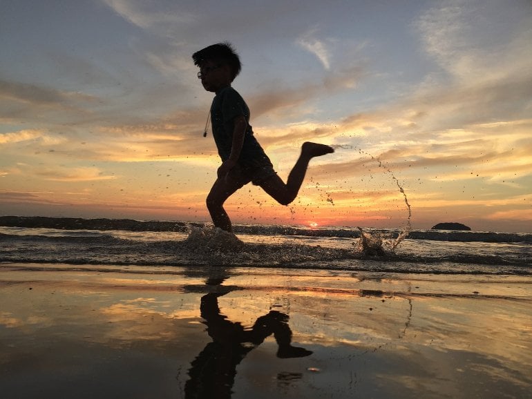 This shows a young boy running on a beach