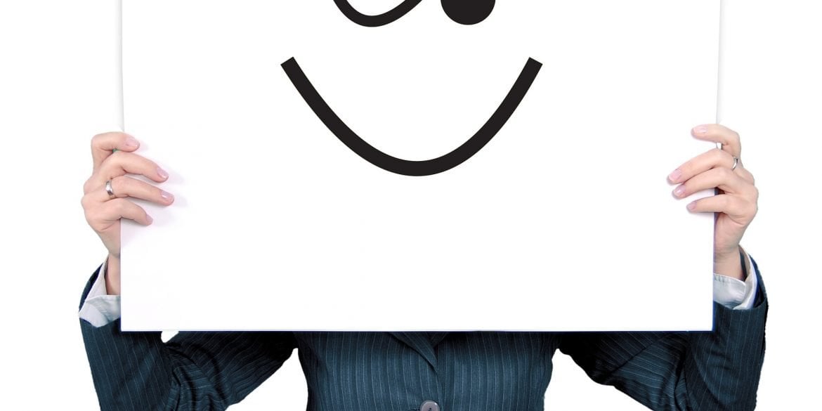 This shows a man holding up a sign with a blinking face drawn on it