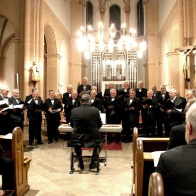 This shows older men singing in a choir